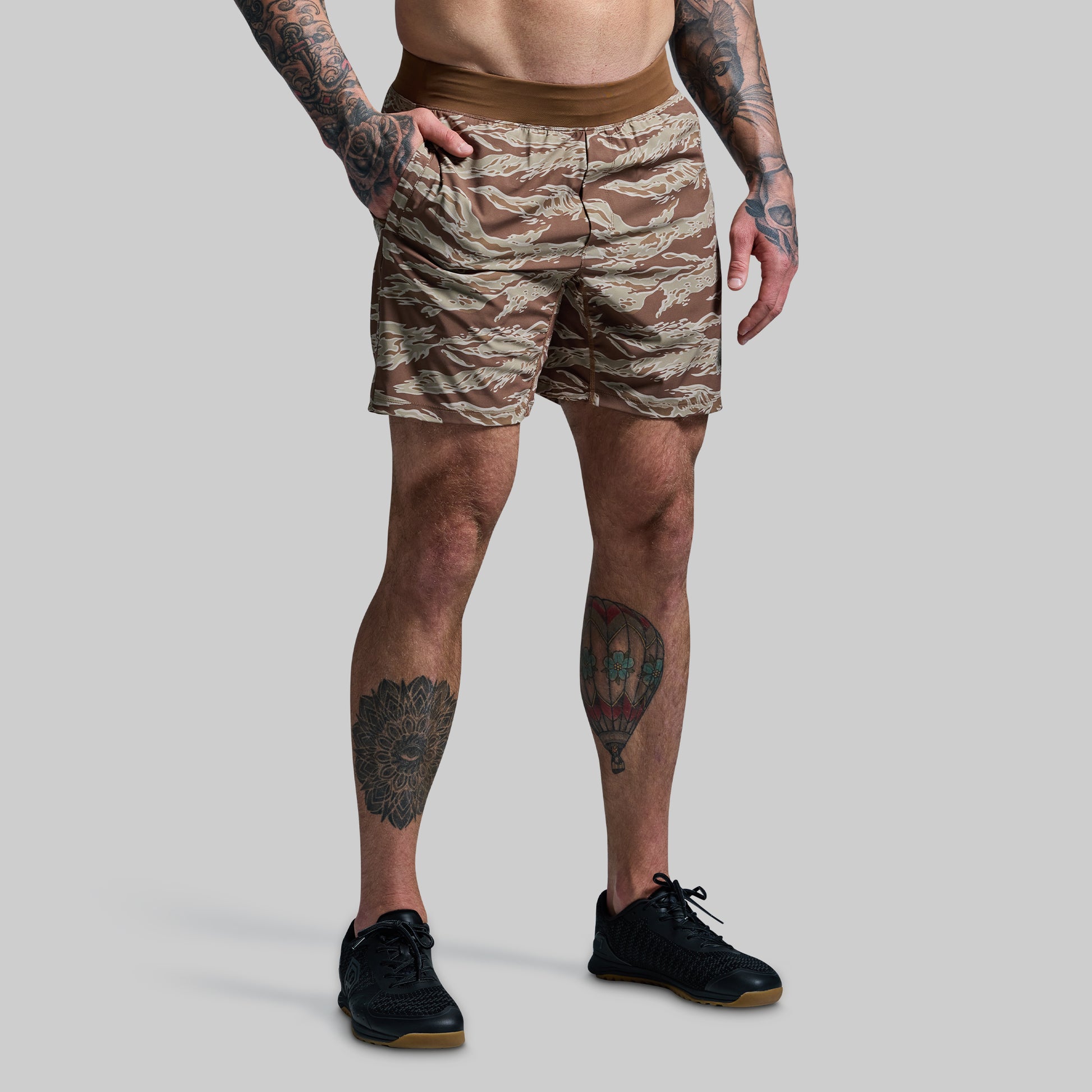 Person wearing camouflage shorts on a plain background