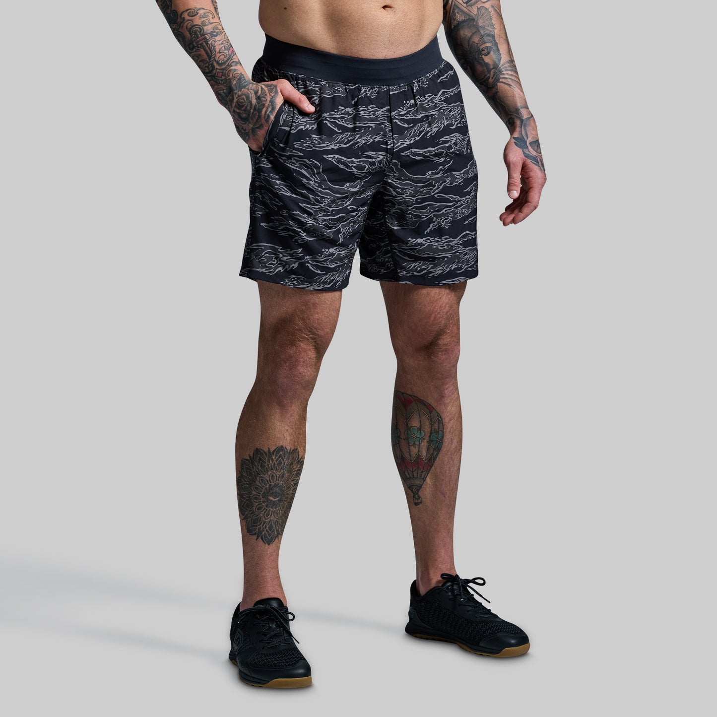 Person wearing black camouflage patterned shorts on a gray background