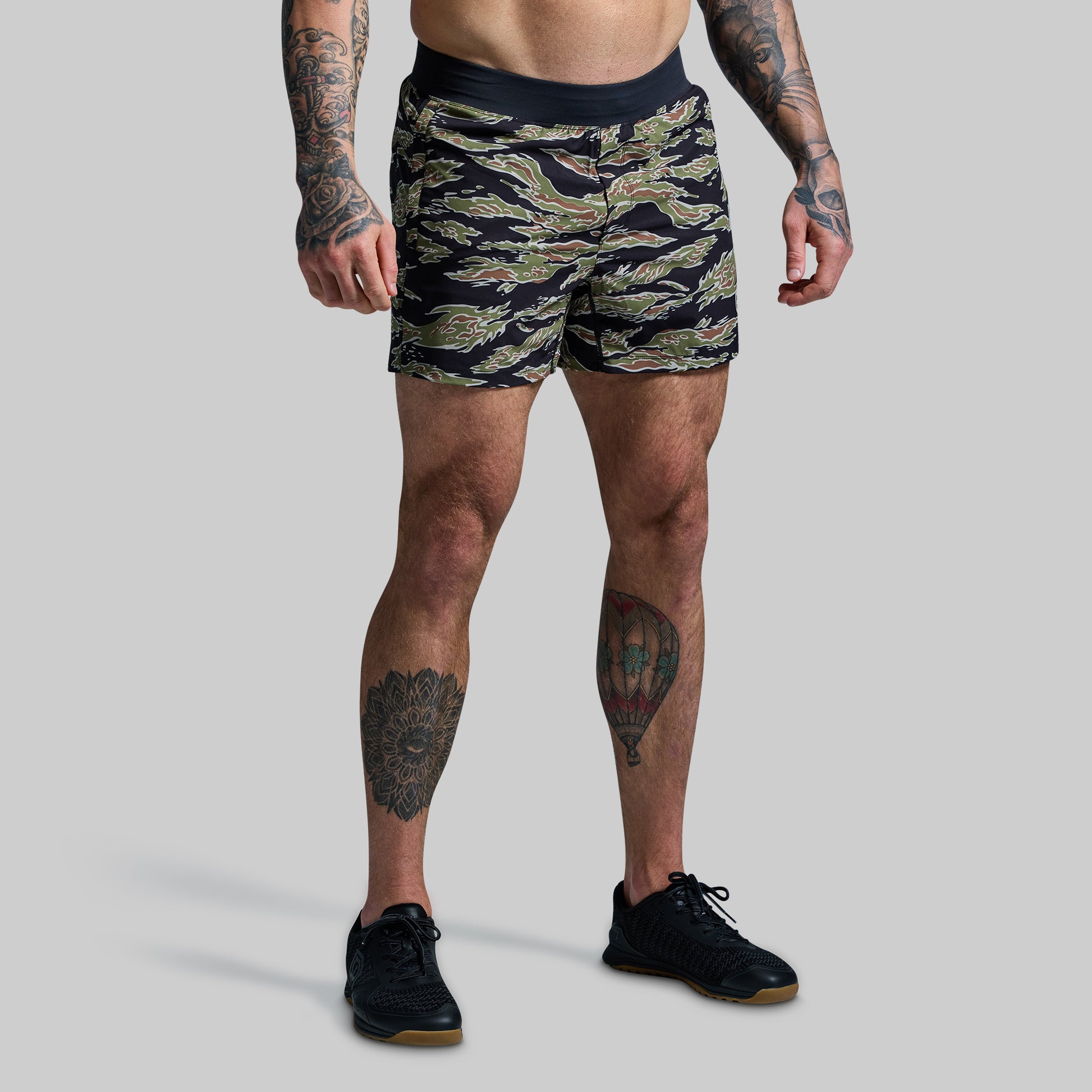Person wearing camouflage shorts on a plain background