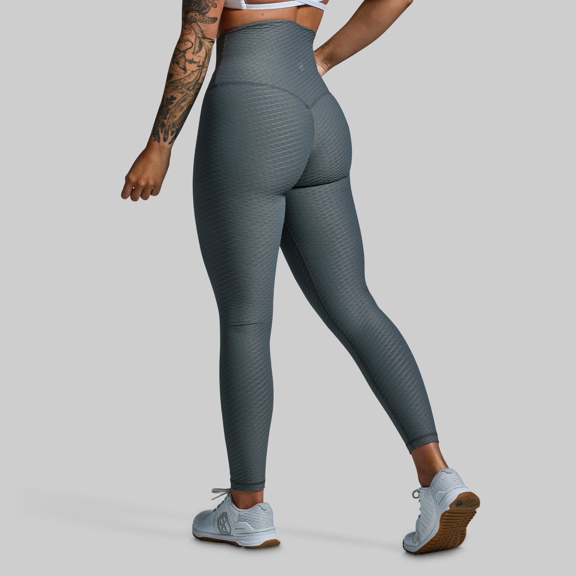 Person wearing gray leggings on a plain background