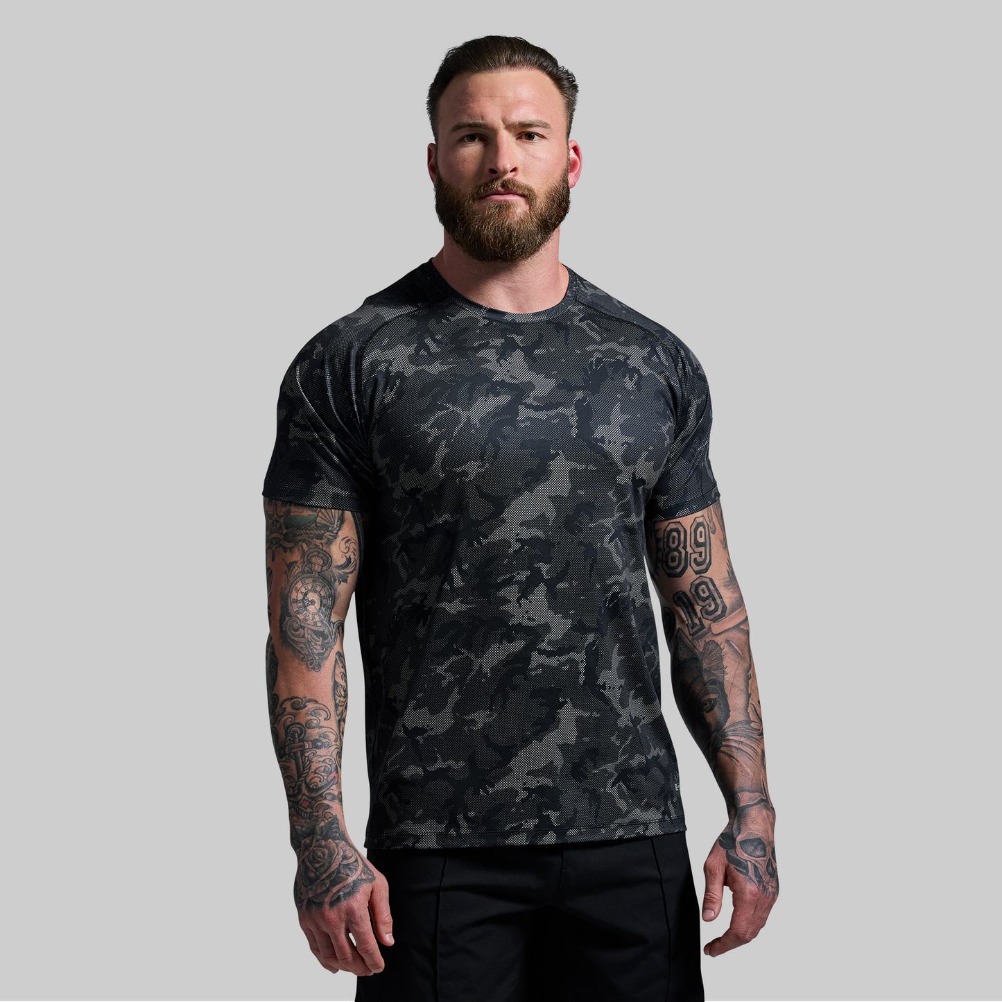 Man wearing a black camouflage t-shirt on a gray background