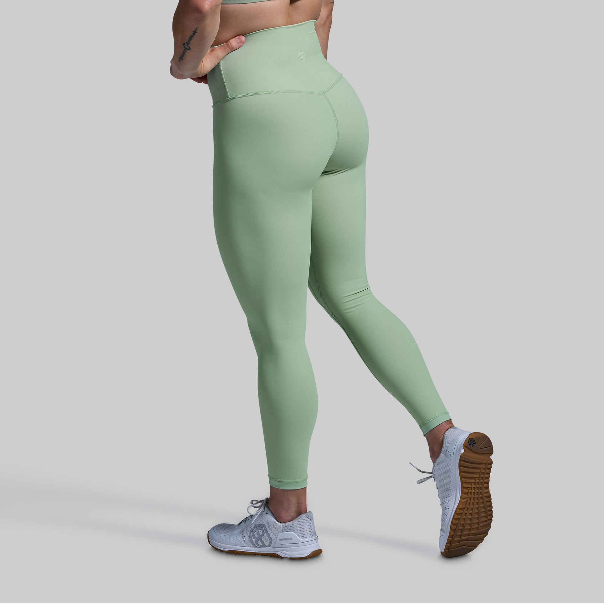 Person wearing light green leggings on a gray background