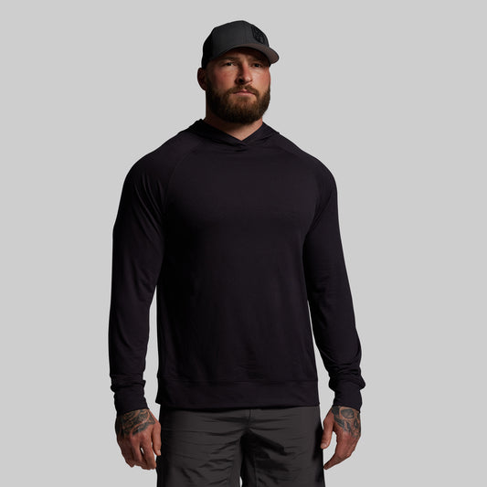 Man wearing a black hoodie and cap on a gray background