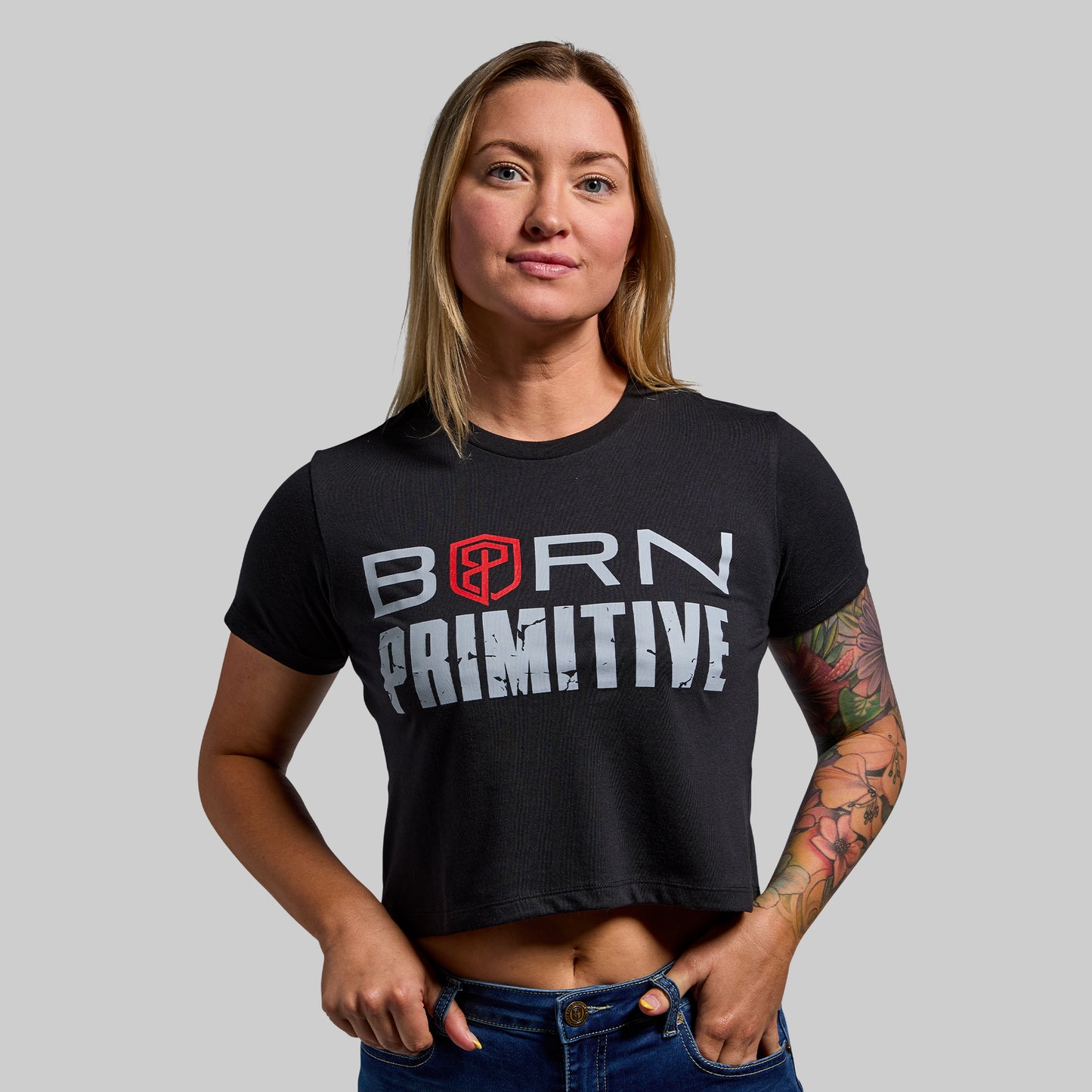 Person wearing a black 'Born Primitive' t-shirt on a gray background