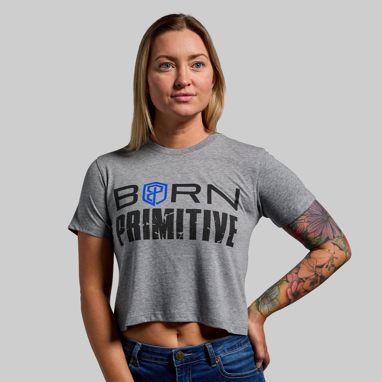Person wearing a gray 'Born Primitive' t-shirt against a plain background