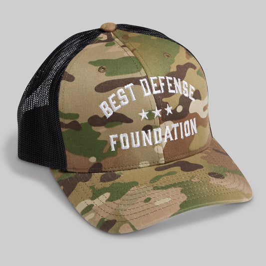 Camouflage cap with 'Best Defense Foundation' text on a gray background