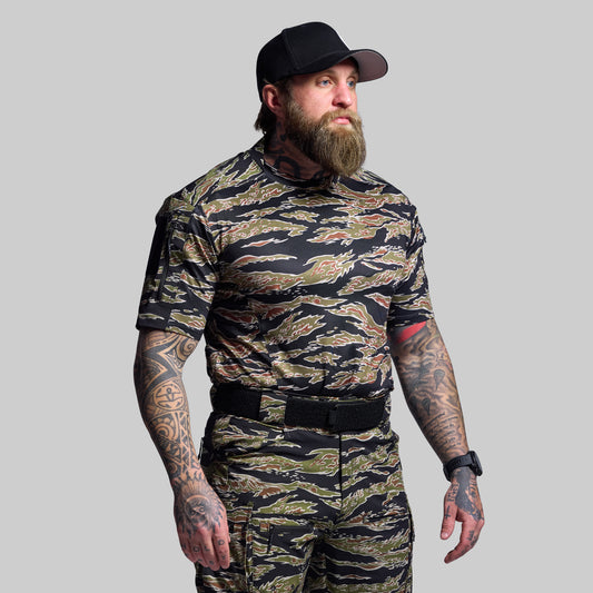 Man wearing a camouflage outfit with a black cap on a gray background