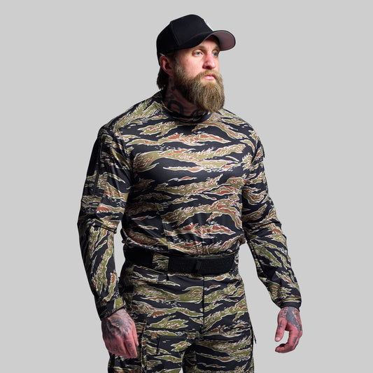 Man wearing a camouflage outfit with a black cap on a gray background