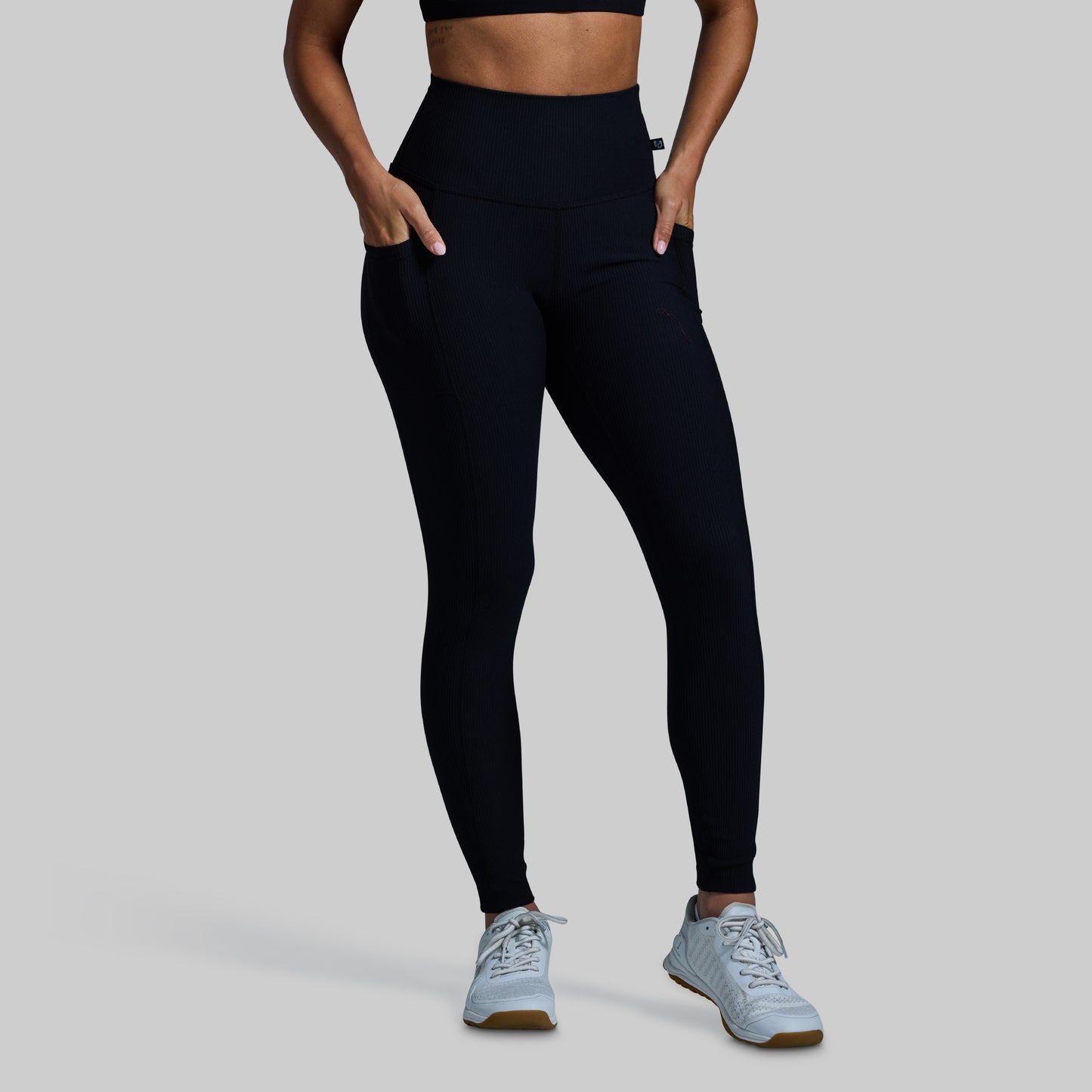 Person wearing black leggings and light blue sneakers on a gray background