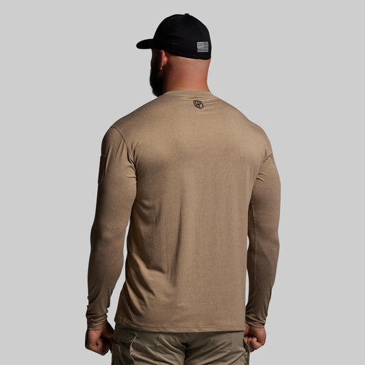 Man wearing a brown long-sleeve shirt and black cap with a flag design on a gray background