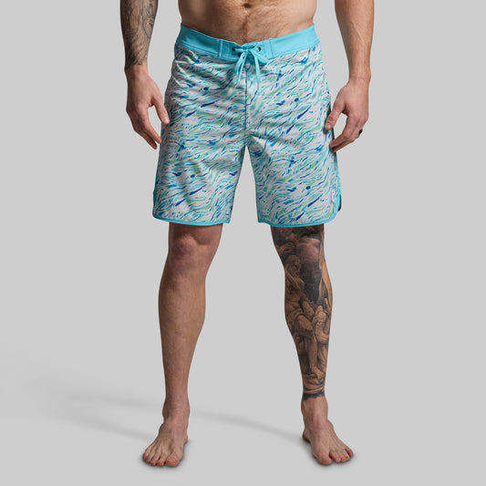 Person wearing blue swim shorts with a pattern on a gray background