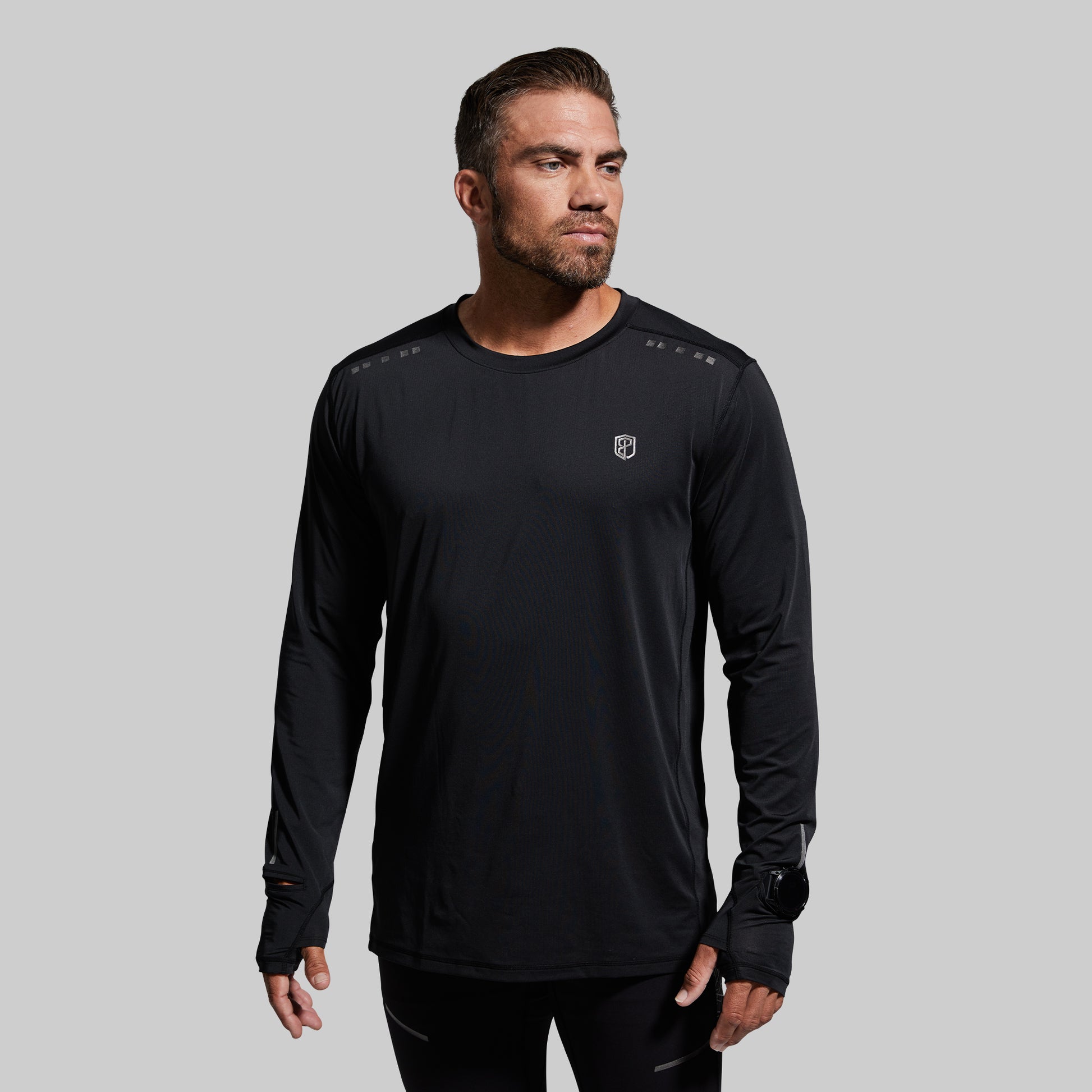 Man wearing a black long-sleeve athletic shirt on a gray background