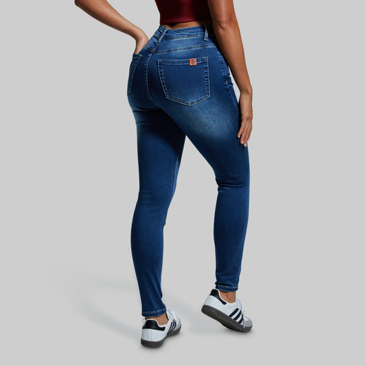 Woman wearing blue skinny jeans on a gray background