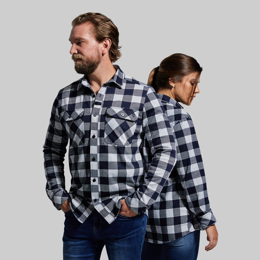 Two people wearing matching blue and white checkered shirts against a gray background