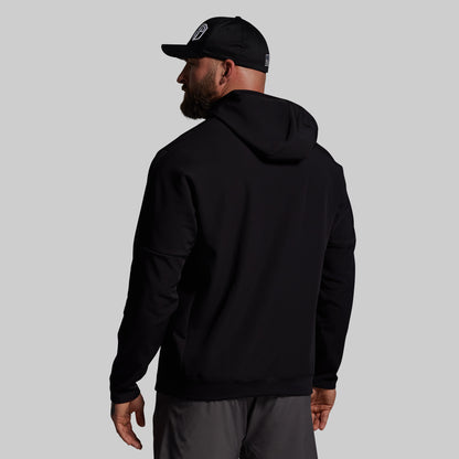 Man wearing a black hoodie and cap on a gray background