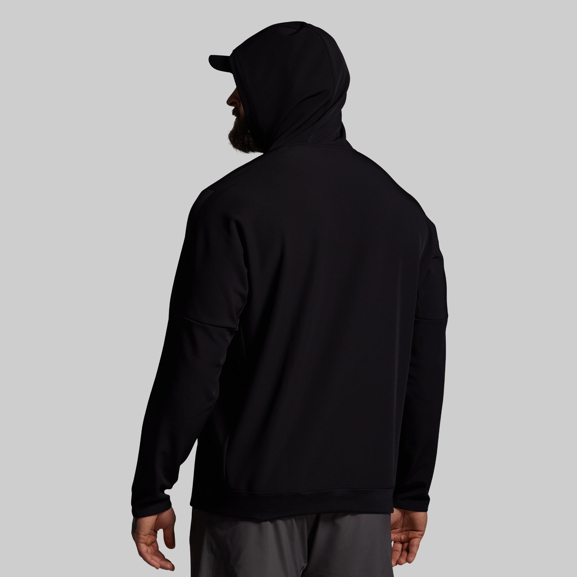 Person wearing a black hoodie and cap on a gray background