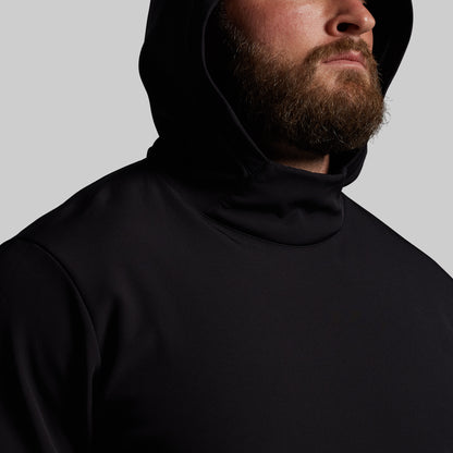 Man wearing a black hoodie against a gray background
