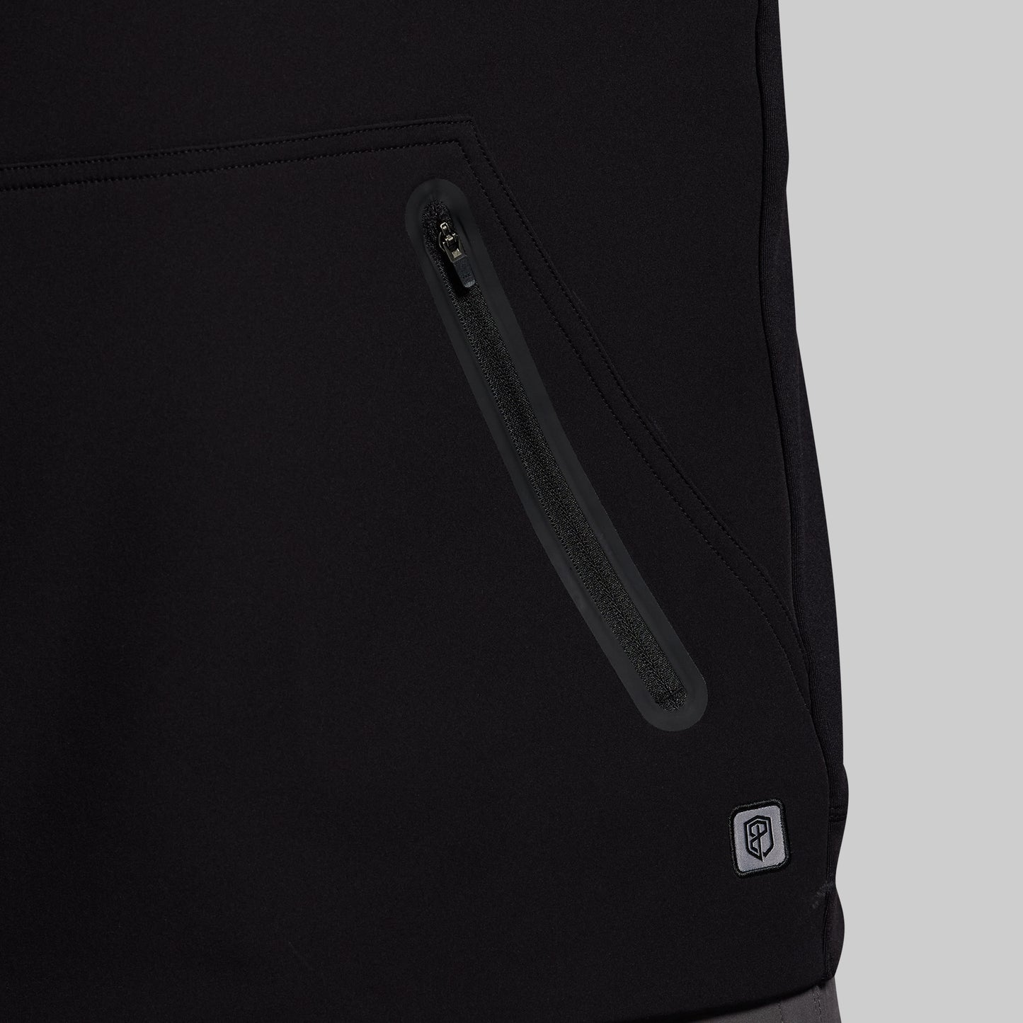 Close-up of a black jacket with a zipper and a brand logo on a light gray background