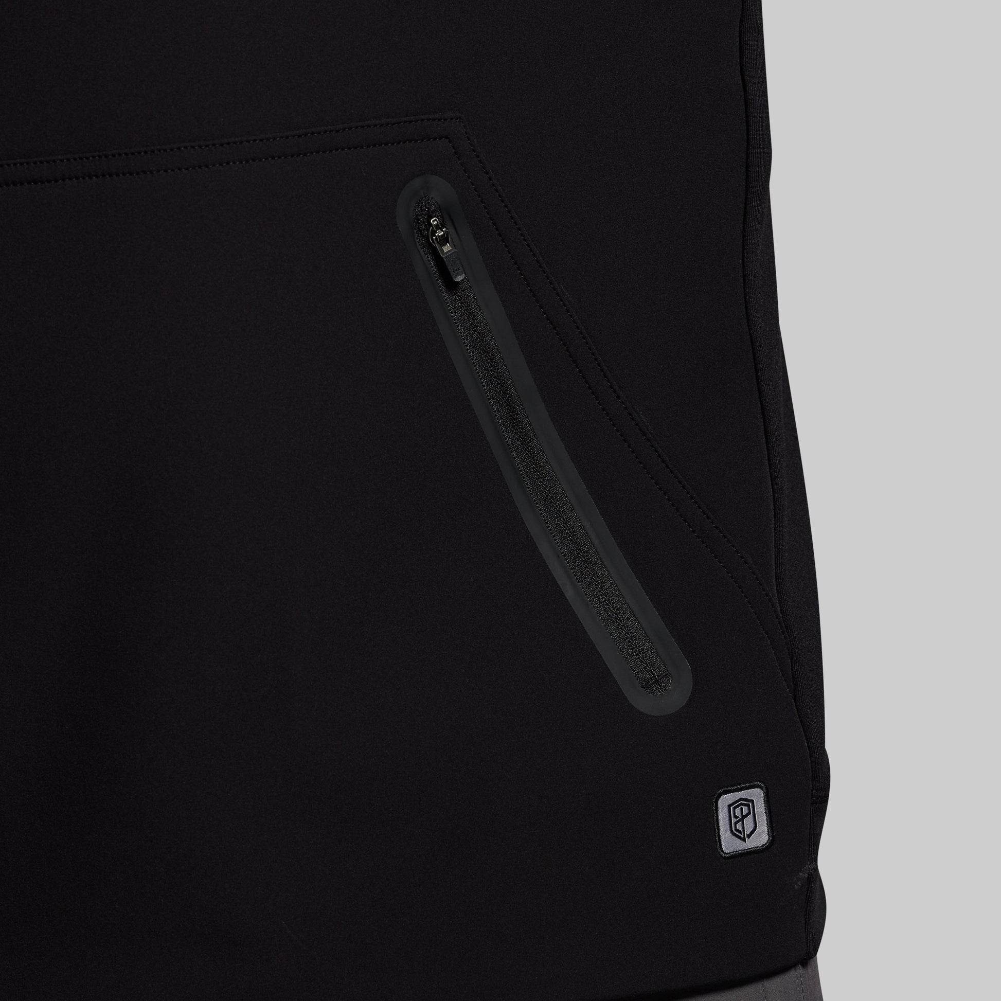 Close-up of a black jacket with a zipper and a brand logo on a light gray background