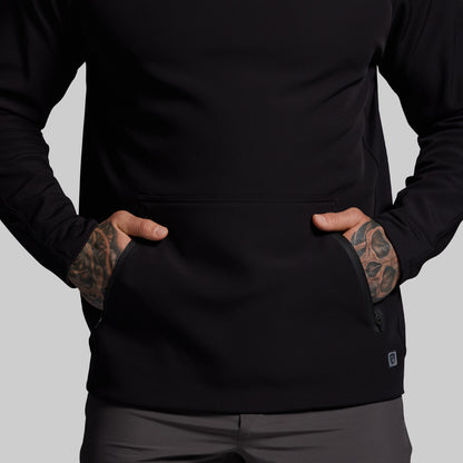 Person wearing a black jacket with tattoos on arms against a gray background