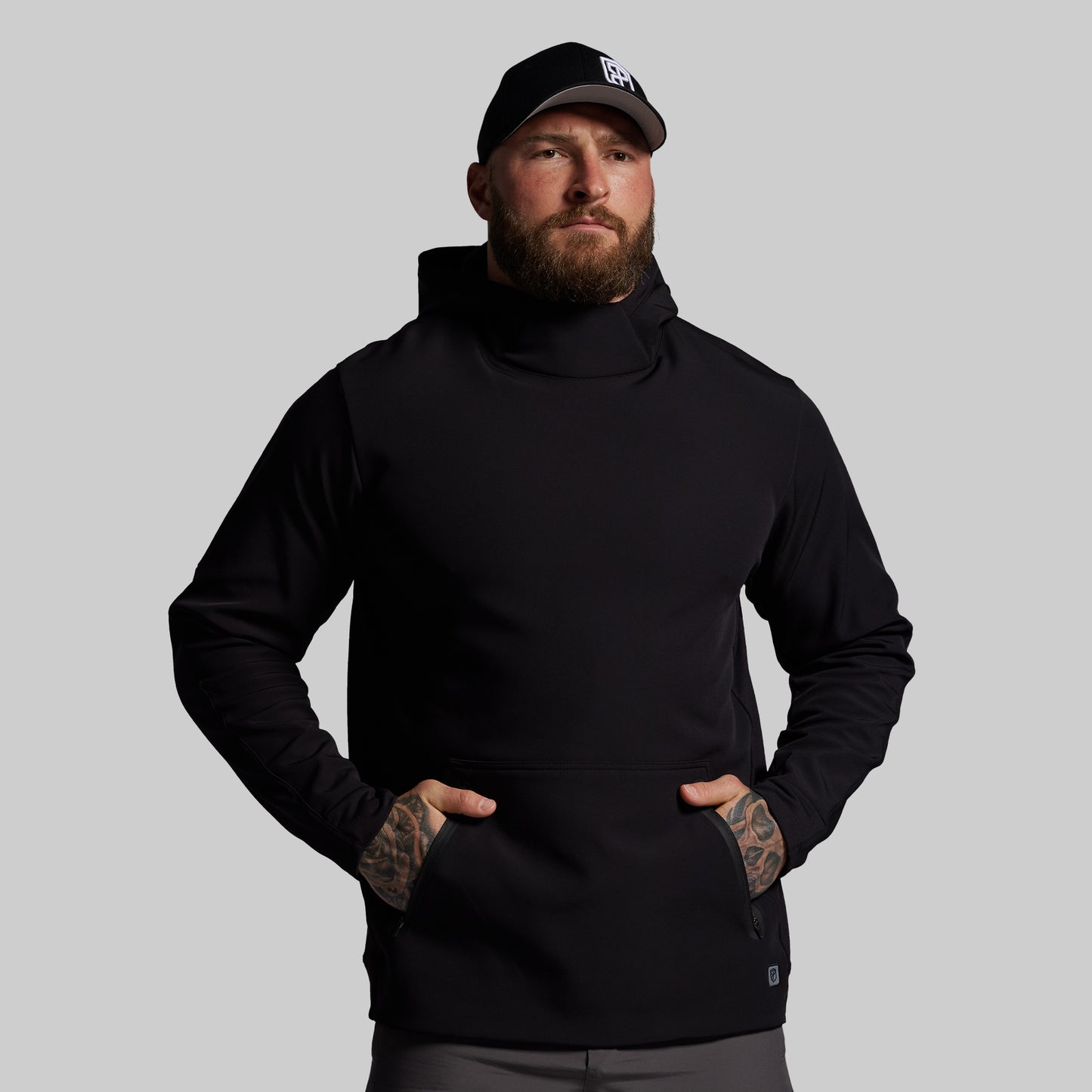 Man wearing a black hoodie and cap on a gray background