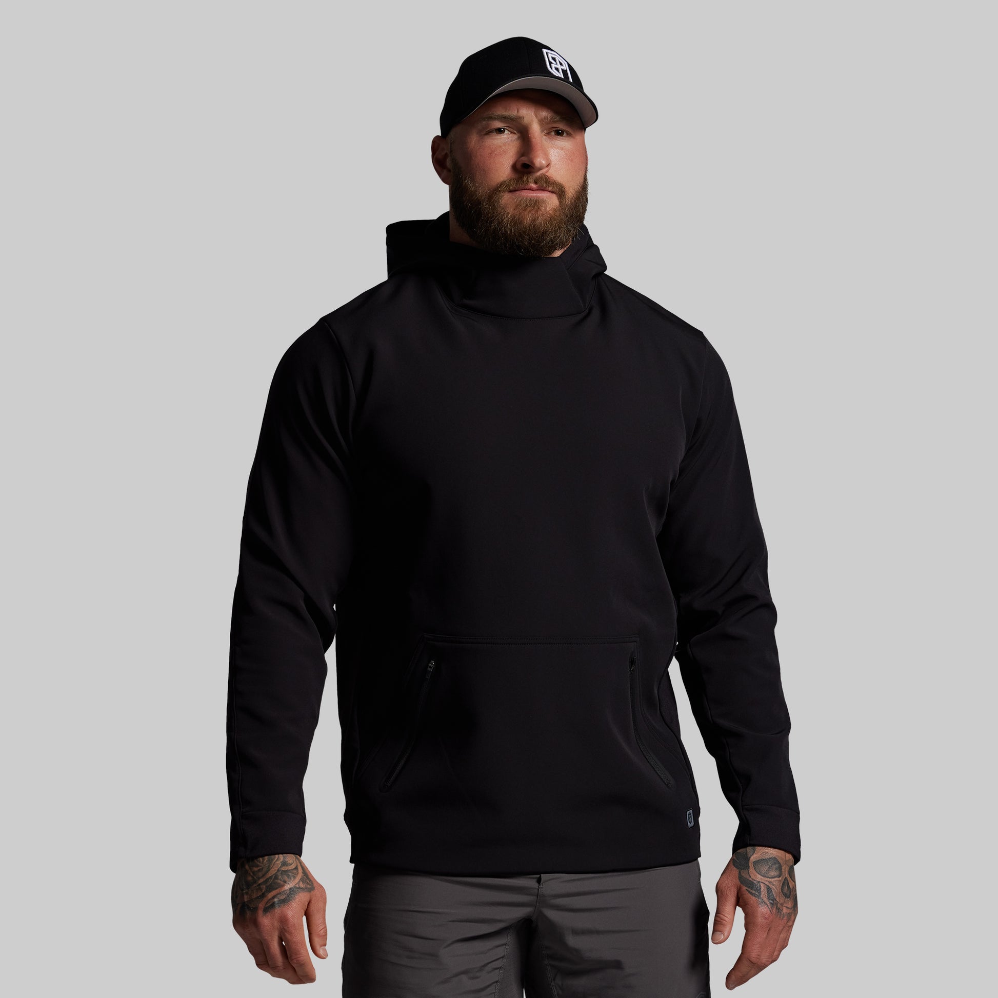 Man wearing a black hoodie and cap on a gray background