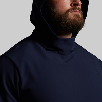 Man wearing a navy blue hoodie against a gray background