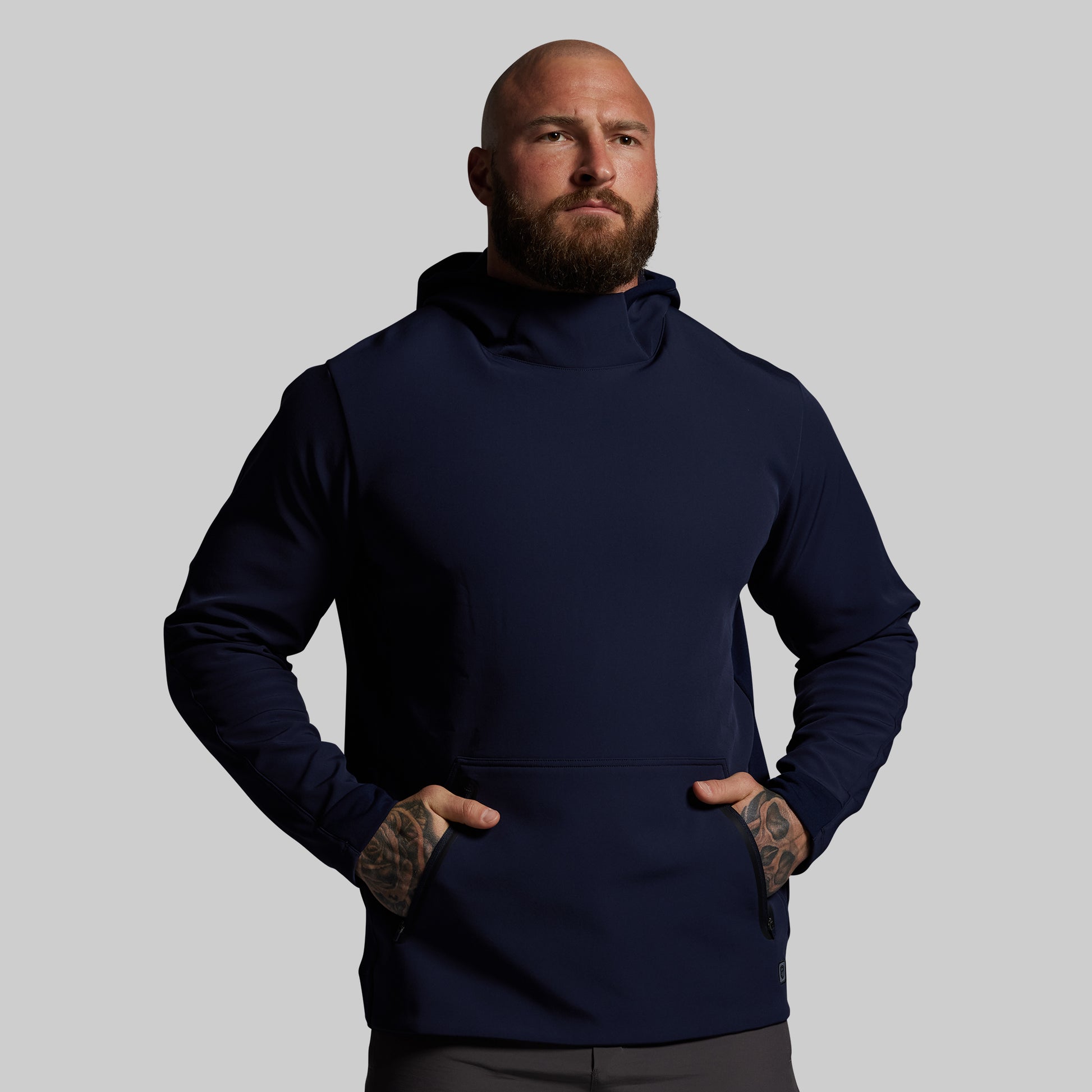 Man wearing a navy blue hoodie against a gray background