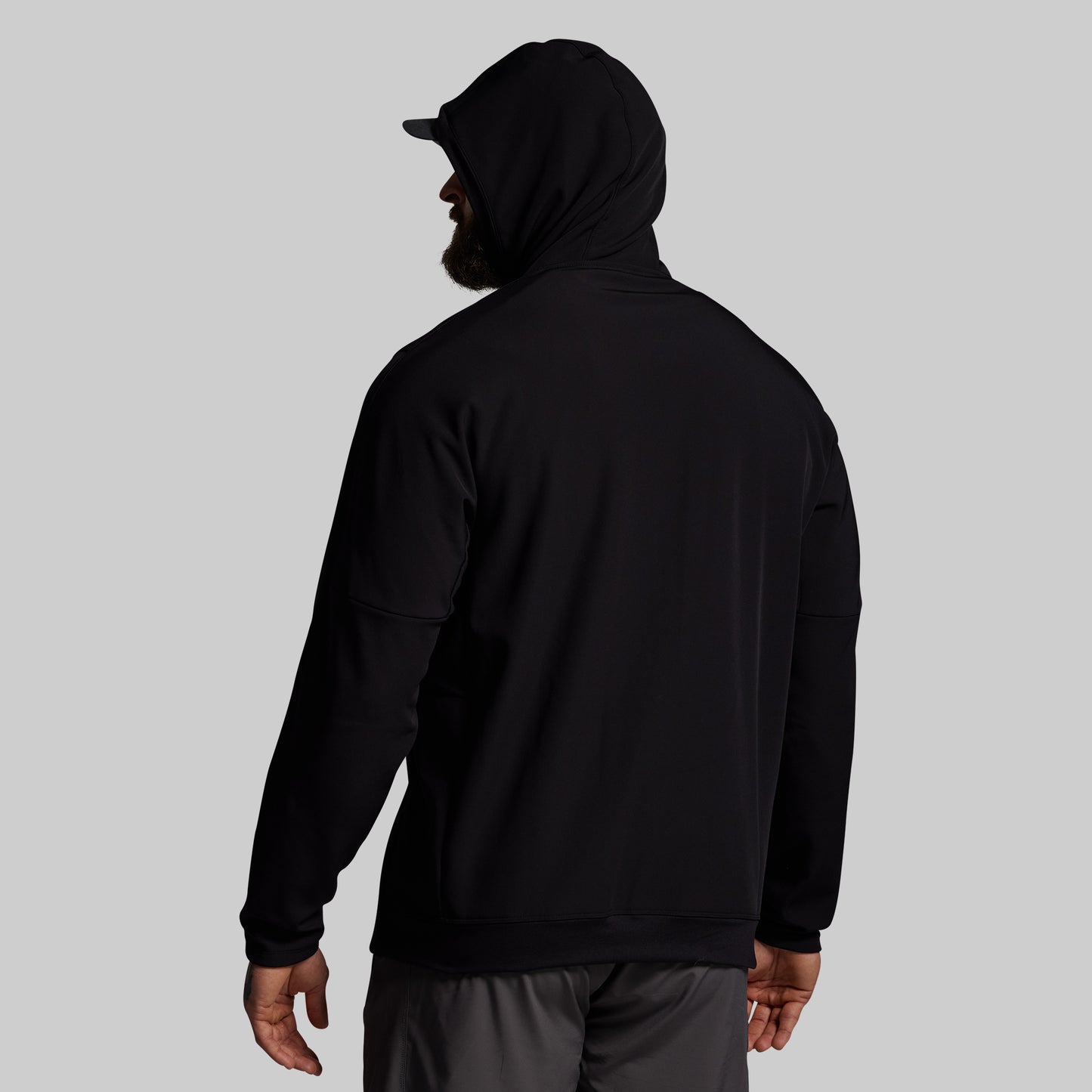 Person wearing a black hoodie and cap on a gray background
