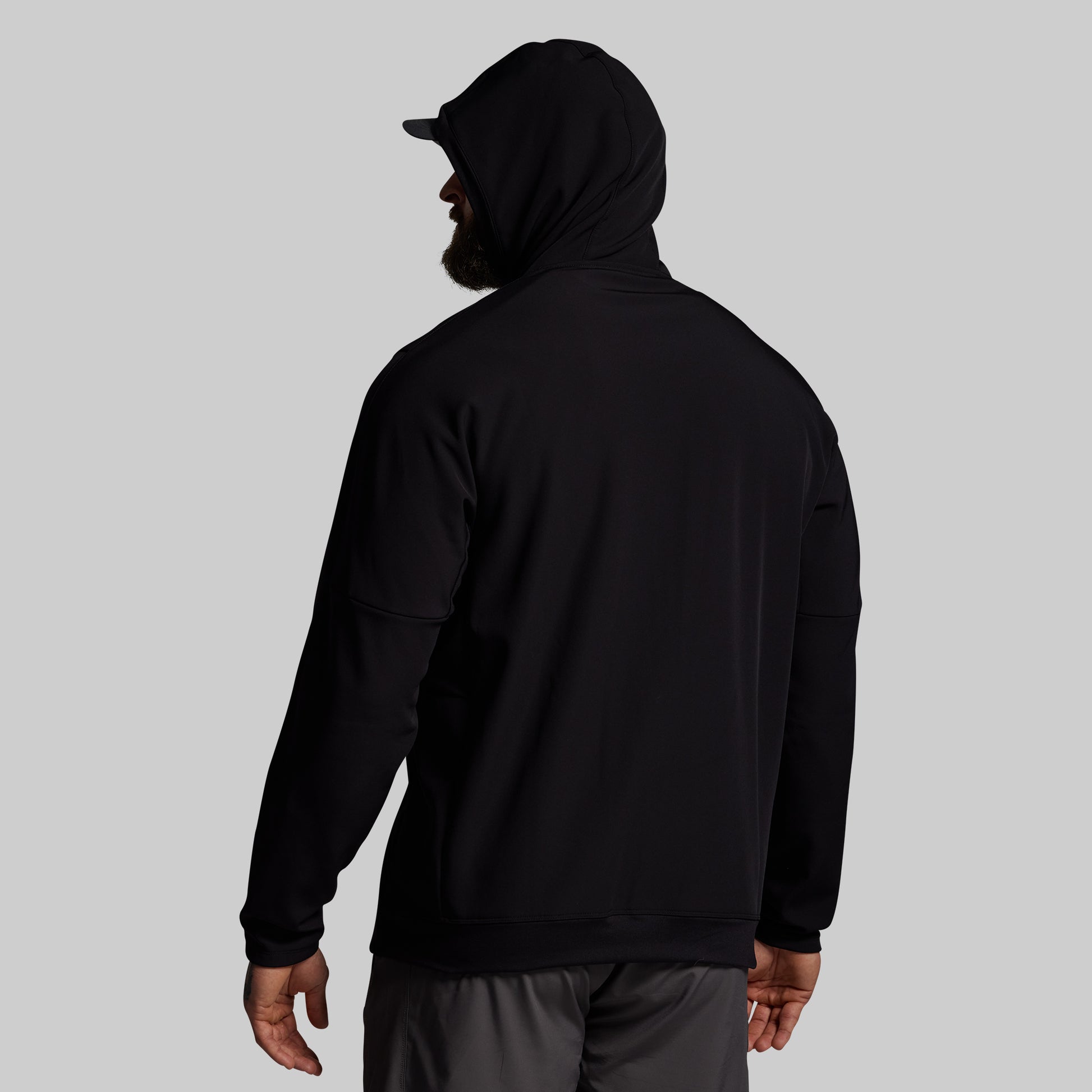 Person wearing a black hoodie and cap on a gray background