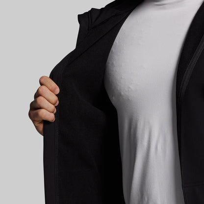 Person wearing a black full zip hoodie over a white shirt on a plain background