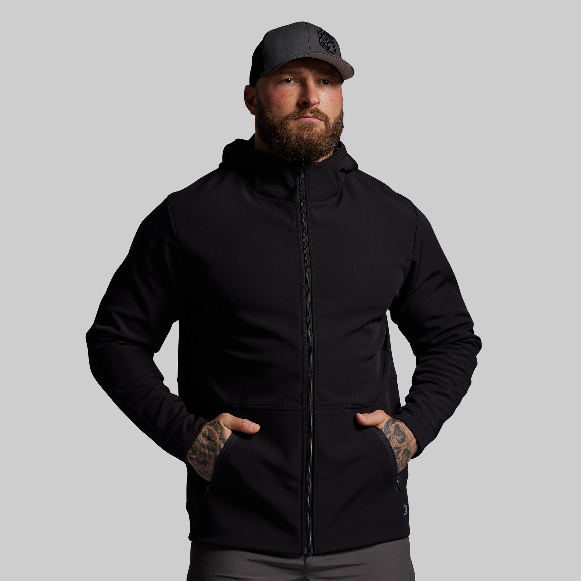 Man wearing a black hoodie and cap on a gray background