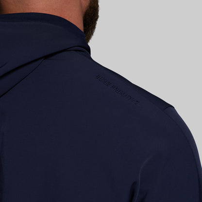 Navy blue jacket with a brand logo on the chest against a gray background