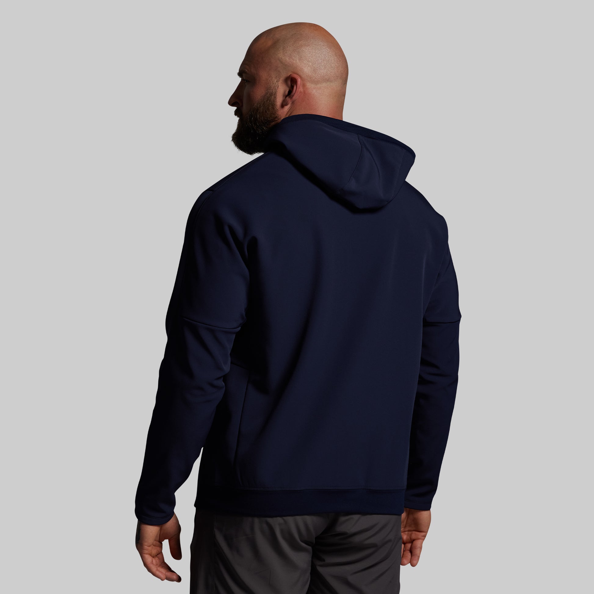 Man wearing a navy blue hoodie on a plain background