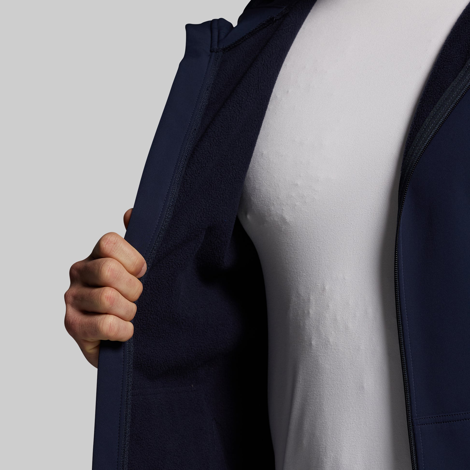 Person wearing a navy blue full zip hoodie over a white shirt on a light gray background