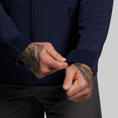 Person wearing a navy jacket with tattooed hands adjusting the sleeve.