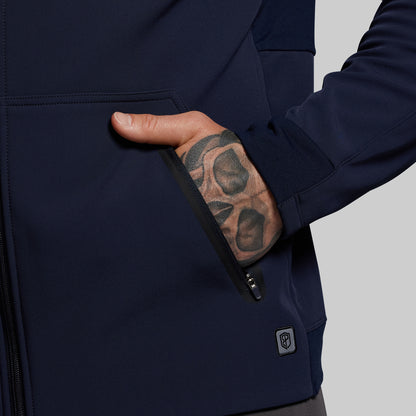 Navy blue jacket with a hand reaching into a pocket, showing a tattooed arm.