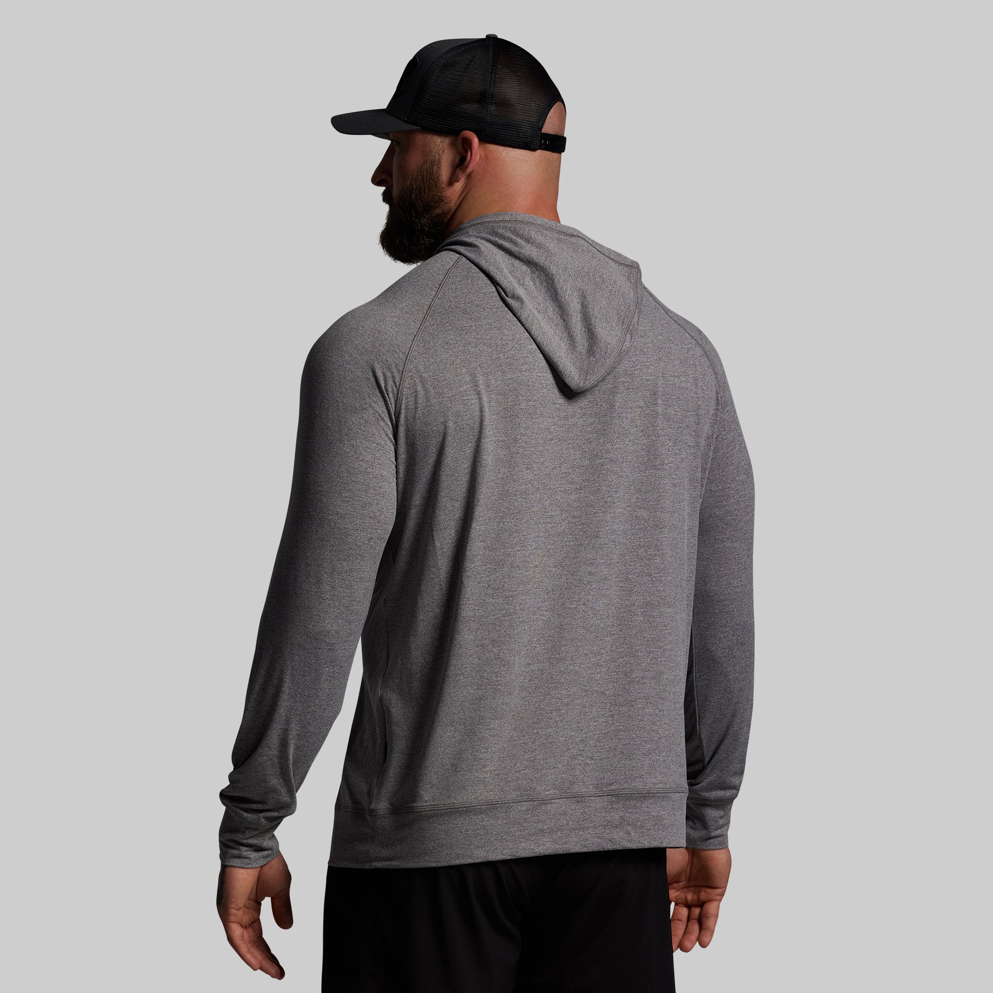 Man wearing a gray hoodie and black cap on a light gray background