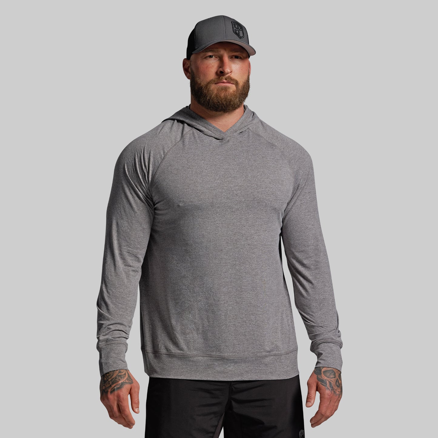 Man wearing a gray long-sleeve hoodie and cap on a light gray background