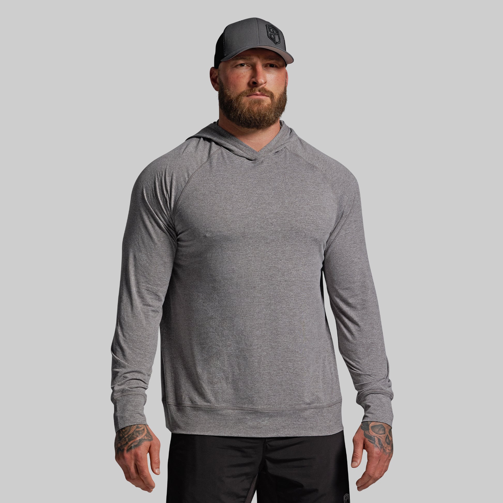 Man wearing a gray long-sleeve hoodie and cap on a light gray background