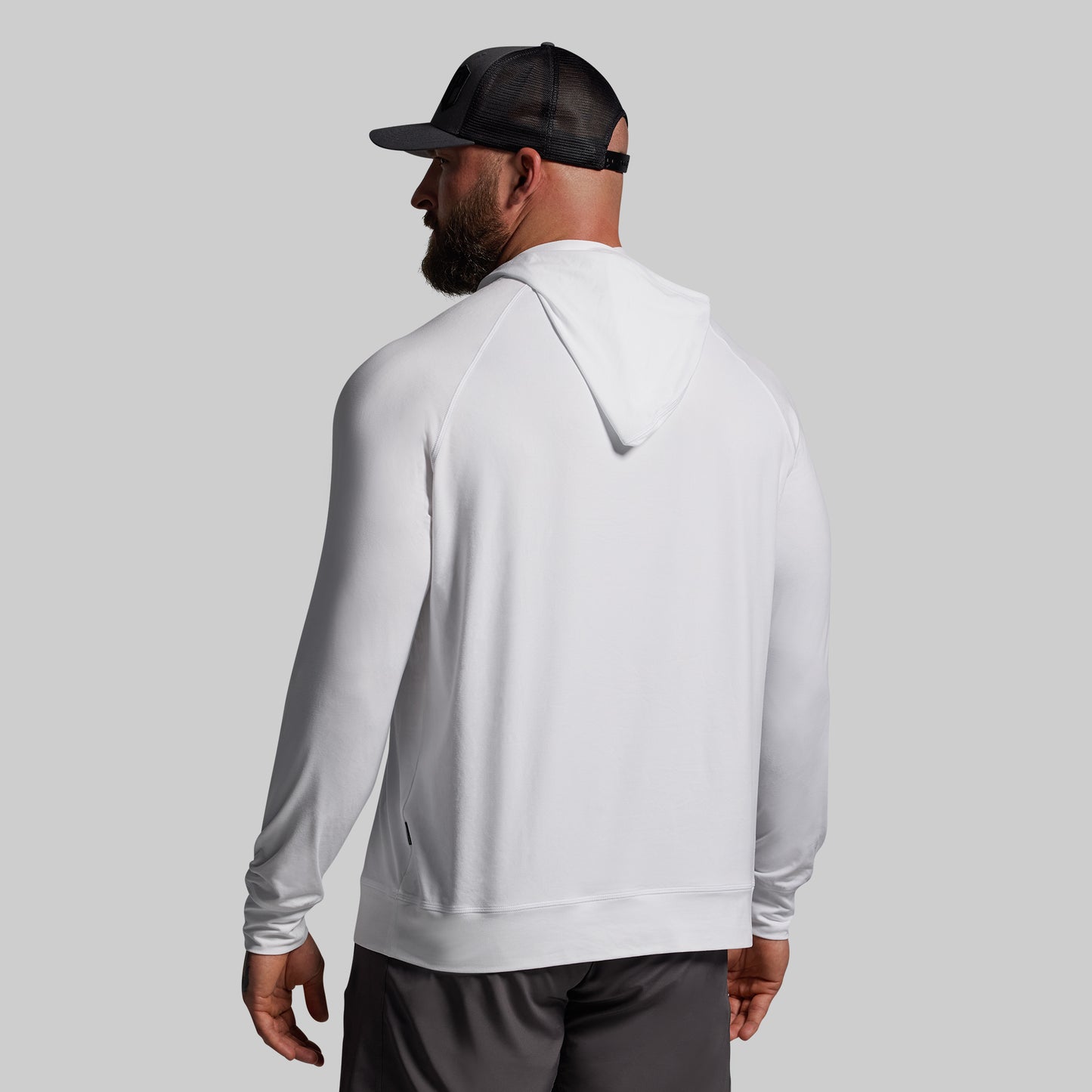 Person wearing a white hoodie and black cap on a gray background