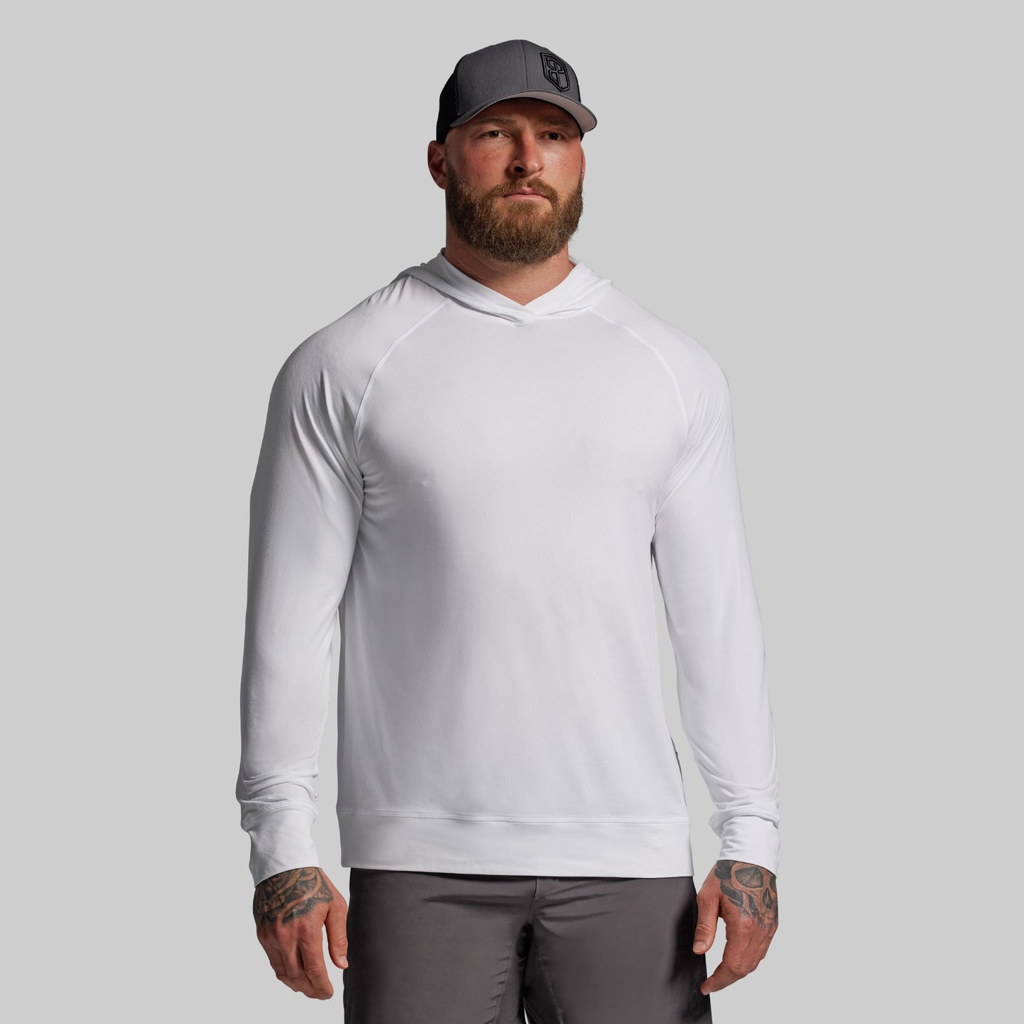 Man wearing a white long-sleeve shirt and gray cap on a gray background