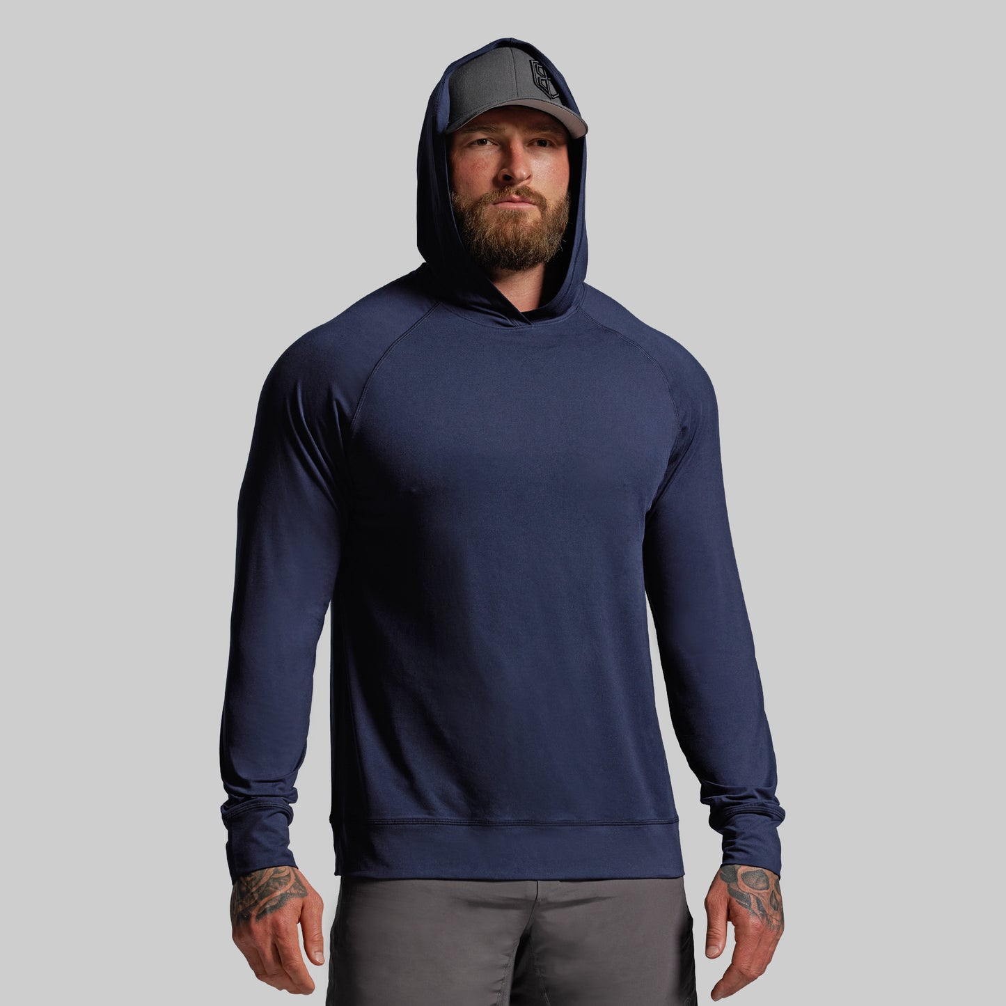 Man wearing a navy blue hoodie and gray cap on a light gray background