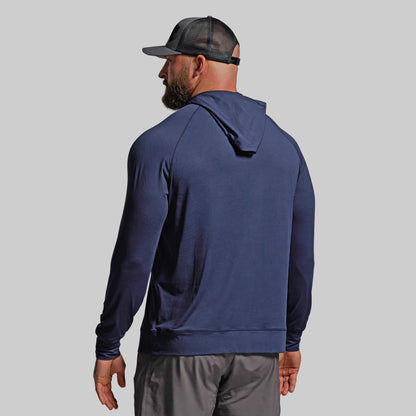 Man wearing a navy blue hoodie and gray pants on a light gray background