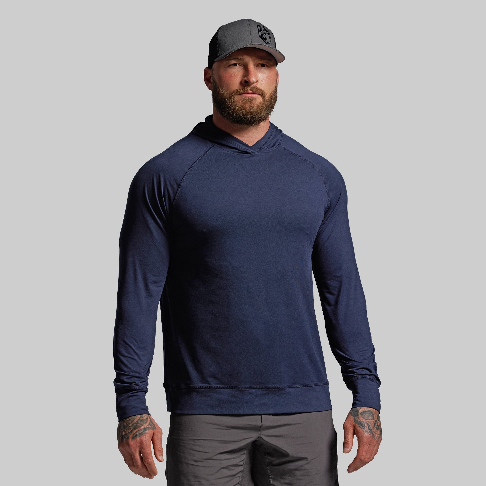 Man wearing a navy blue hoodie and gray cap on a light gray background