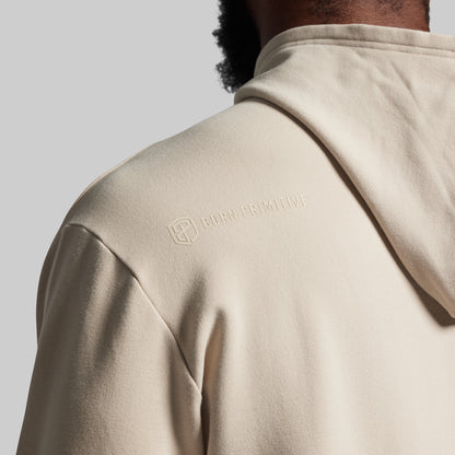 Beige hoodie with a brand logo on the shoulder against a gray background