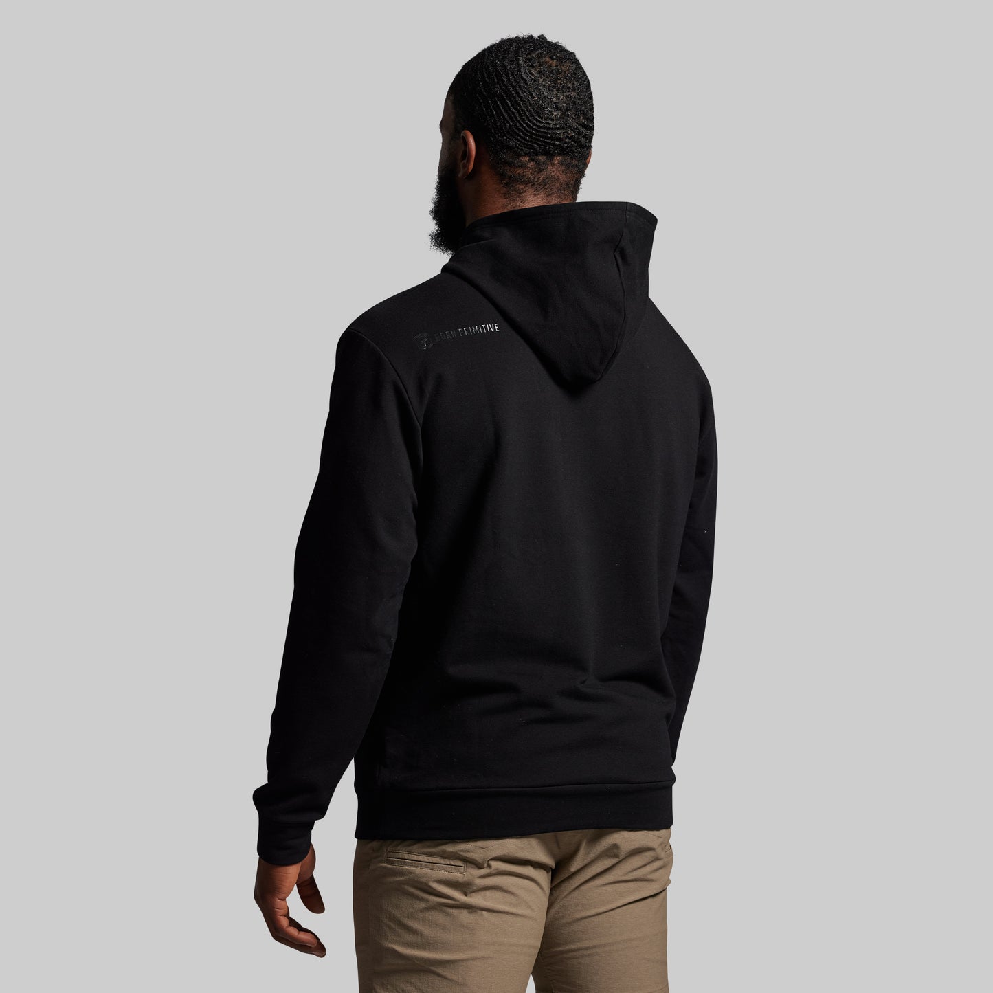 Person wearing a black hoodie with text on the back against a gray background