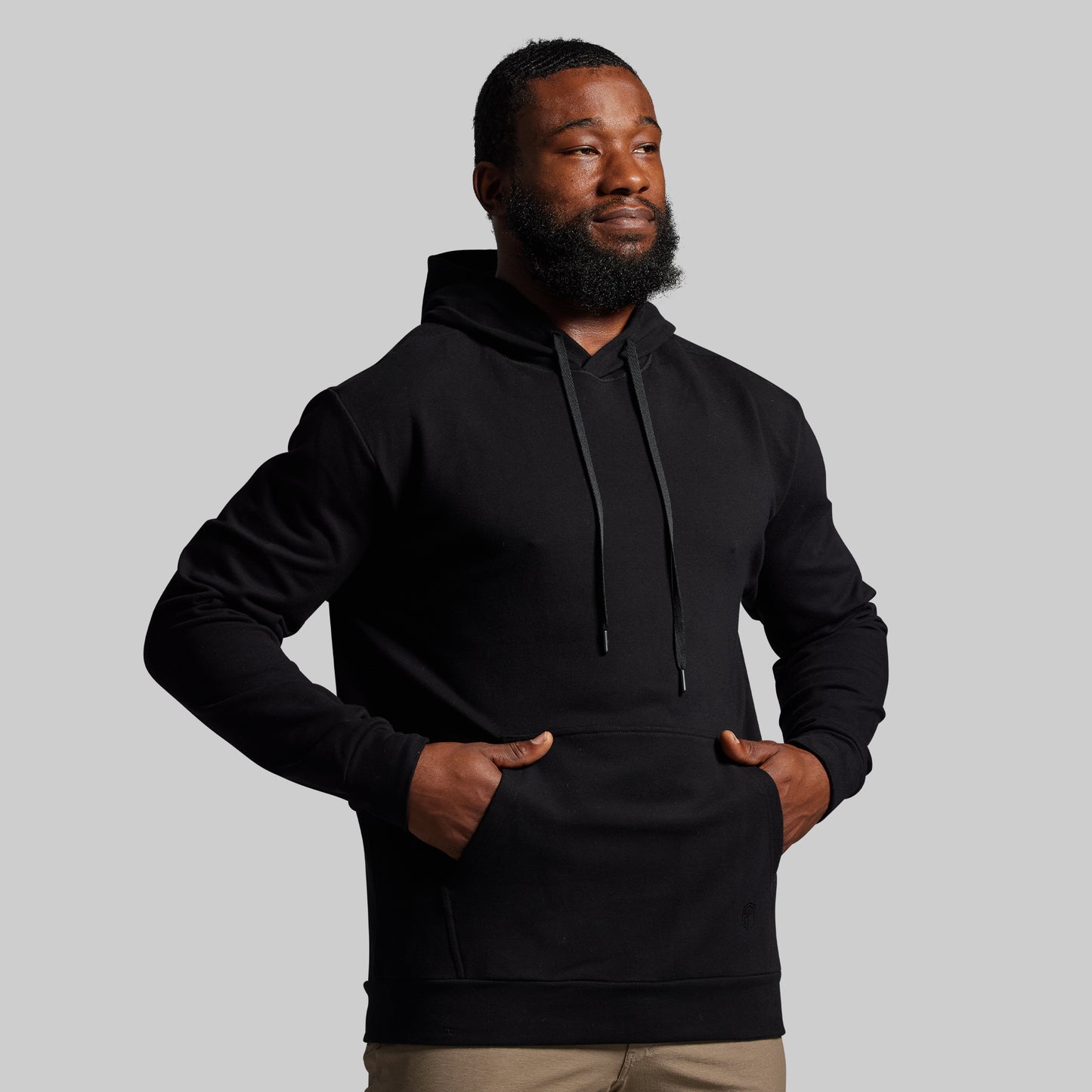 Man wearing a black hoodie against a gray background