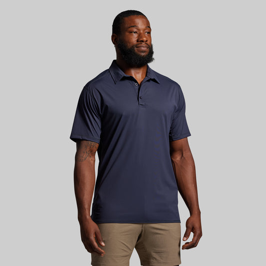 Man wearing a navy blue polo shirt against a gray background