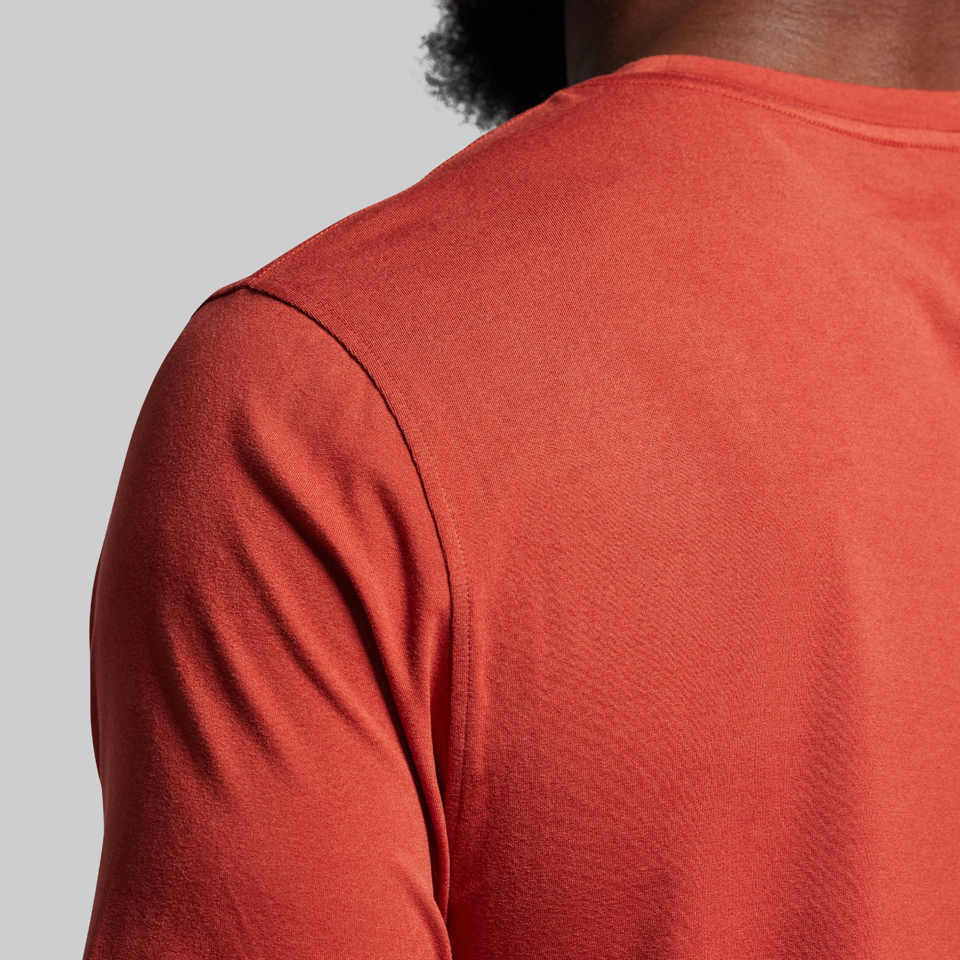 Close-up of a person wearing a red shirt on a gray background.